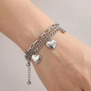 Detail of multilayer silver stainless steel bracelet featuring heart pendants and bead clasp