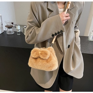 Brown plush bucket bag with bow detail and leather strap shown in a stylish cafe setting