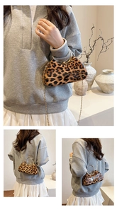 Detail view of leopard print box bag featuring gold circular handle and ball clasp closure