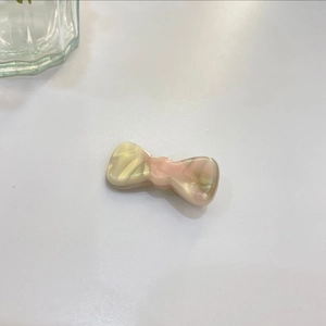 Detail of a handmade white and pink bow hair clip with polished pearlescent finish