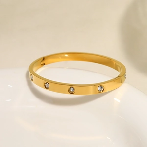 Detailed macro view of a gold-plated stainless steel oval bangle set with ten clear zircons
