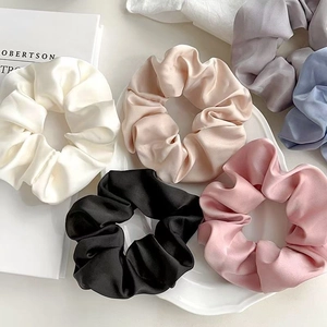 Set di elastici in raso in vari colori su piatto in ceramica per styling capelli eleganti