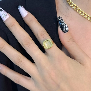 Bague dorée élégante avec pierre d'opale beige carrée et manucure artistique sur la main