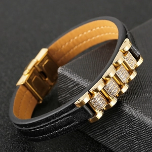 Detailed close-up of golden stainless steel bracelet with cubic zirconia and black leather
