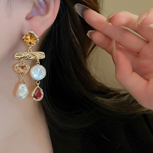 Close-up of vintage baroque earrings with heart crystals, pearls and red teardrop pendants