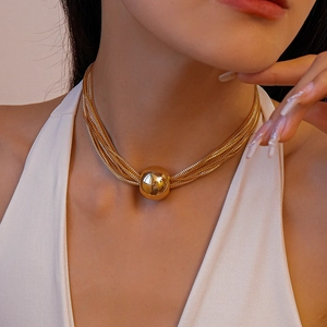 Detail of multi-layer gold necklace with central bead on model's collarbone