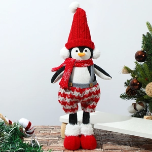 Detail of Christmas penguin plush with red knitted hat and plaid scarf in festive setting