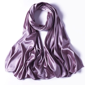 Detailed view of the smooth glossy texture of a purple satin scarf on a white background