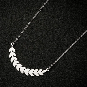 Macro shot of silver wheat ear pendant on black textured background showing polished finish