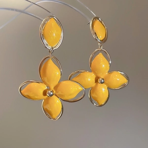 Détail de boucles d'oreilles fleurs jaunes avec cadre doré et pétales en émail brillant