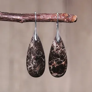 Close-up of teardrop imperial stone earrings with natural brown marble textures on branches