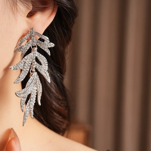 Close-up of silver leaf tassel earrings with sparkling rhinestones worn by a model