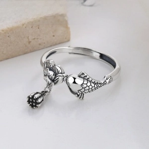 Macro detail of silver ring featuring traditional koi fish, lotus, and seed pod elements
