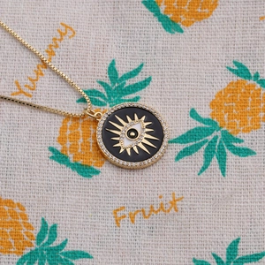 Close-up of gold plated evil eye pendant with black enamel and sparkling zircons
