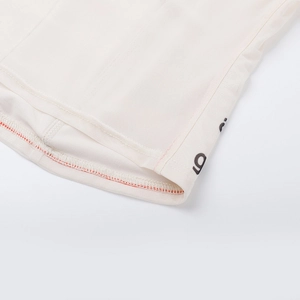 Detail der cremeweißen Stofftextur mit feiner oranger Naht und schwarzem Grafikdruck
