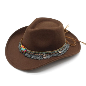 Détail d'un chapeau de cowboy en feutre marron avec perles ethniques et pompon gris