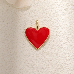 Golden heart pendant with red enamel inlay on a minimalist textured background