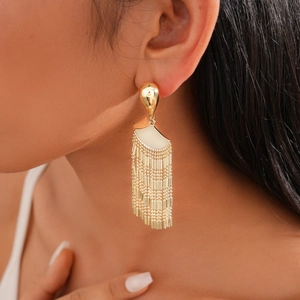 Close-up of golden tassel fan earrings on model showing shiny metallic texture