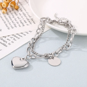 Detail of silver dual-layer chain bracelet featuring Cuban links and heart pendant