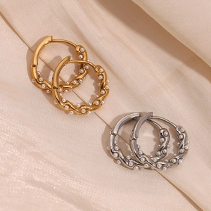 Detailed shot of gold and silver twisted hoop earrings featuring intricate pearl clusters