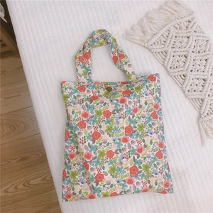 Gros plan d'un mini sac cabas en toile fleurie avec un bouton-pression en métal doré vintage