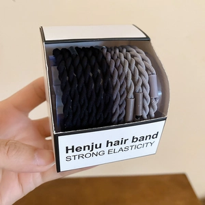 Détail d'élastiques à cheveux tressés noirs et gris dans leur boîte de présentation