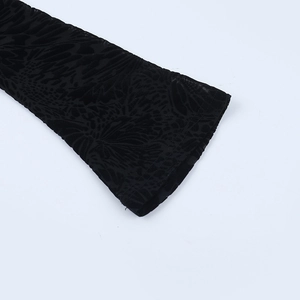 Detail of black flocked lace bodysuit showing sheer mesh texture and floral cuff design
