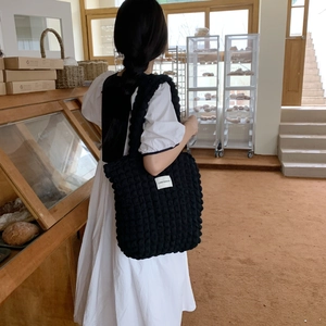 Detailed view of black bubble textured fabric and white brand label on a puffy tote bag
