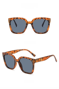 Detail view of tortoiseshell square sunglasses with grey lenses and gold stud accents