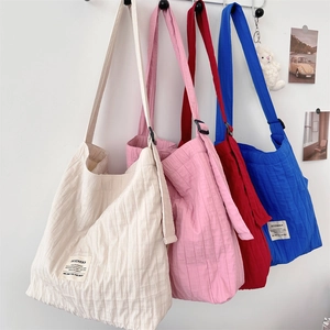 Detailed texture of pleated canvas tote bags in white, pink, red and blue options