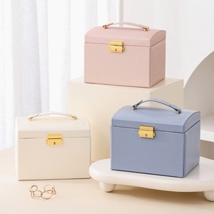 Three-tier faux leather jewelry box with handle and gold lock in pink, blue, and white