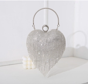 Detail of silver heart-shaped clutch with rhinestone tassels and a ring handle
