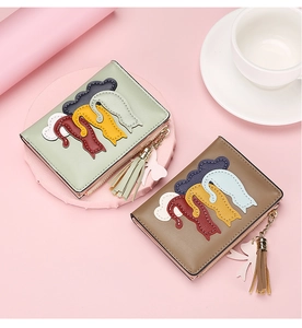 Detailed shot of mint green and brown PU leather wallets with cat embroidery and tassels