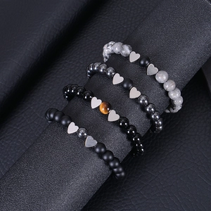 Detailed view of beaded bracelets with heart pendants on a textured black display
