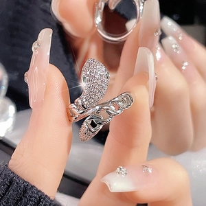 Macro detail of silver snake ring with pavé zircons and green gemstone eyes on model