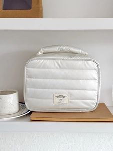 Detail of white quilted nylon makeup bag with pearlescent finish and carry handle