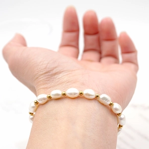 Bracciale regolabile in perle d'acqua dolce e perline dorate da donna sfondo bianco