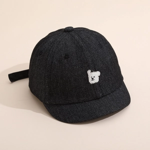Détail d'une casquette en denim noir pour bébé avec broderie d'ourson blanc