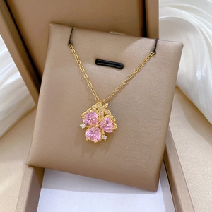 Macro shot of gold floral necklace with three pink heart stones in a jewelry gift box