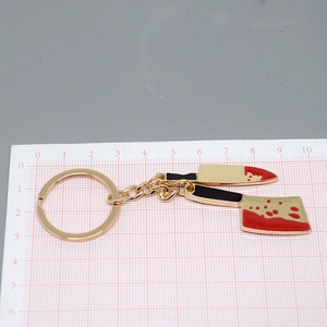 Macro detail of alloy mini blood-stained cleaver pendants on a pink cutting mat