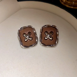 Macro shot of vintage brown button earrings with silver stitching details on a jewelry tray