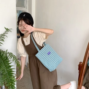 Detailed view of blue and white checkered wool tote bag styled with a feminine outfit
