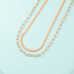 Macro detail of rose gold double-layer herringbone snake chain and paperclip link necklace