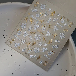 Detailed macro shot of Co-478 nail stickers with 3D white flowers and gold leaf accents