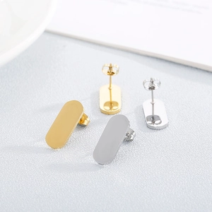 Golden and silver oval stud earrings set on a minimalist textured surface lifestyle backdrop
