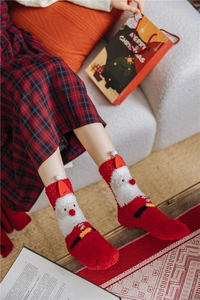 Detail of Christmas Santa plush coral fleece socks with 3D pom pom decor in red