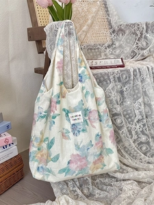 Vintage floral linen tote bag with lace detail on a rustic wooden chair backdrop