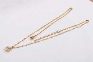 Dettaglio della collana con cuore dorato, zircone trasparente e chiusura a moschettone