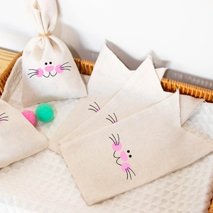 Easter bunny linen gift bags with cute rabbit face prints in a woven basket