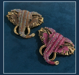 Macro shot of elephant brooches with colorful AB and pink rhinestones on blue velvet background